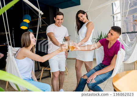 Cheerful friends in the pub. Drinking beer, talking, having fun. Cheerful friends in the pub. Drinking beer, talking, having fun. 136862023