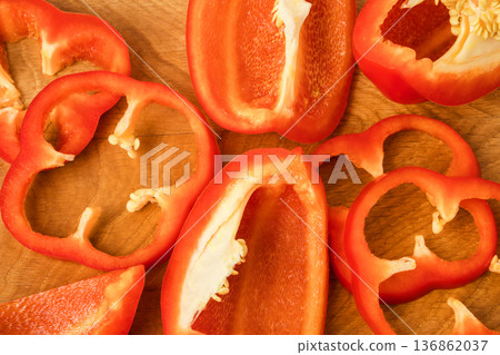Sliced pieces, parts, lobes of sweet pepper, red, scattered on a wooden board Sliced pieces, parts, lobes of sweet pepper, red, scattered on a wooden board 136862037