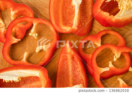 Sliced pieces, parts, lobes of sweet pepper, red, scattered on a wooden board 136862038
