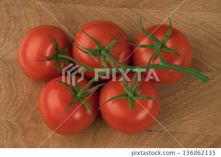 Green branch with five red tomatoes on a wooden board 136862135
