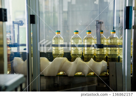 Bottling line of sunflower oil in bottles. Vegetable oil production plant Bottling line of sunflower oil in bottles. Vegetable oil production plant 136862157