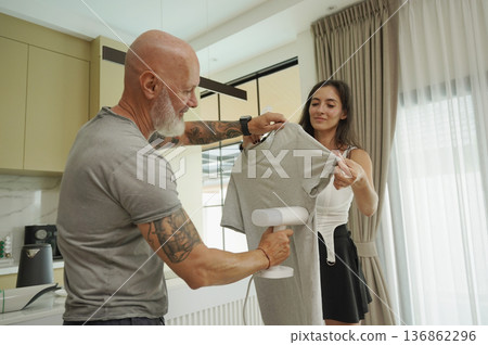 A couple ironing a t-shirt with a steam iron. A couple ironing a t-shirt with a steam iron. 136862296