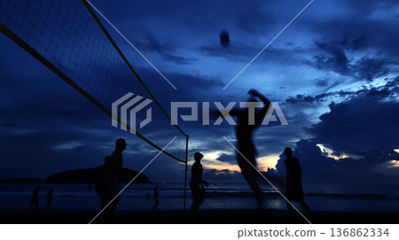 Young people playing beach volleyball by the ocean at sunset Young people playing beach volleyball by the ocean at sunset 136862334