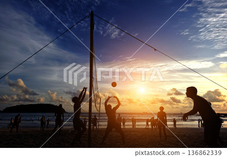 Young people playing beach volleyball by the ocean at sunset Young people playing beach volleyball by the ocean at sunset 136862339