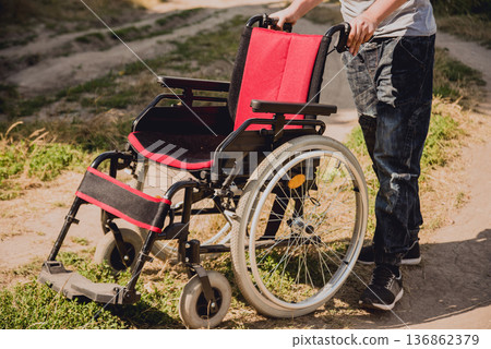 Disabled man resting in a campsite with friends. Wheelchair in the forest Disabled man resting in a campsite with friends. Wheelchair in the forest 136862379