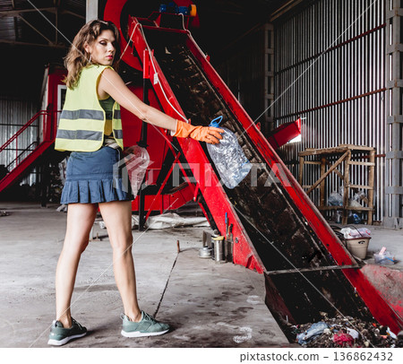 Woman-volunteer sorting trash at modern recycling plant. 136862432