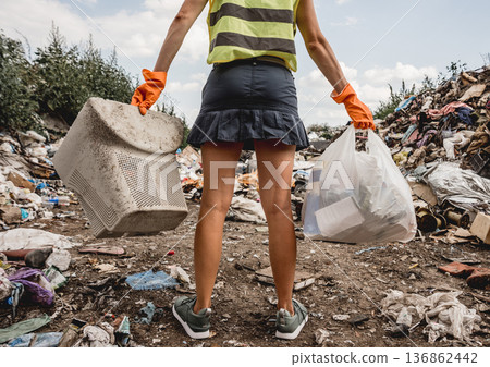 Woman volunteer helps clean the field of plastic garbage. Woman volunteer helps clean the field of plastic garbage. 136862442
