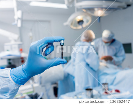 Spinal surgery. Surgeon show polyaxial screw in operating room Spinal surgery. Surgeon show polyaxial screw in operating room 136862447