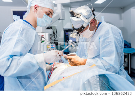 Spinal surgery. Group of surgeons in operating room with surgery equipment. 136862453