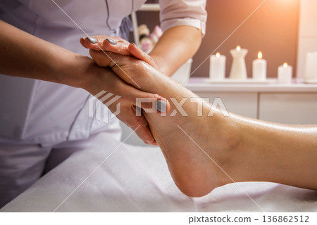 Beautiful young woman enjoying foot massage in spa salon. Cosmetology 136862512
