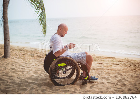 Disabled man in a wheelchair on the beach. Disabled man in a wheelchair on the beach. 136862764