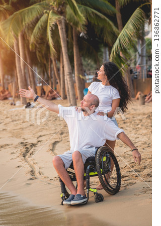 Disabled man in a wheelchair with his wife on the beach. Disabled man in a wheelchair with his wife on the beach. 136862771