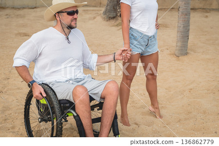 Disabled man in a wheelchair with his wife on the beach. Disabled man in a wheelchair with his wife on the beach. 136862779