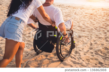 Disabled man in a wheelchair with his wife on the beach. Disabled man in a wheelchair with his wife on the beach. 136862808