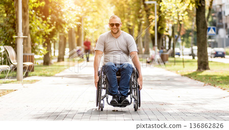Handicapped man in wheelchair walk at the park alley Handicapped man in wheelchair walk at the park alley 136862826
