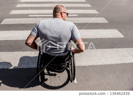 Handicapped man in wheelchair crossing street road Handicapped man in wheelchair crossing street road 136862836