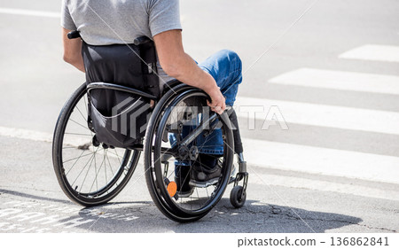 Handicapped man in wheelchair preparing to cross the road on pedestrian crossing Handicapped man in wheelchair preparing to cross the road on pedestrian crossing 136862841