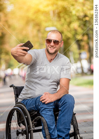 Handicapped man in wheelchair at the park alley use a smartphone 136862844