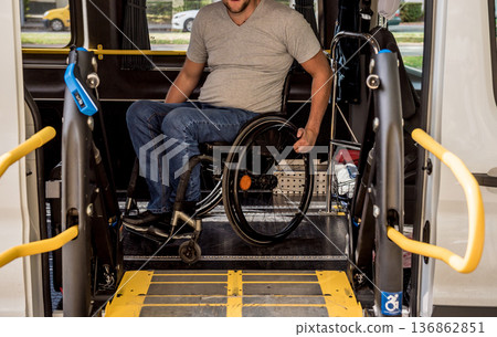 A man in a wheelchair on a lift of a vehicle for people with disabilities 136862851