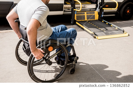 A man in a wheelchair moves to the lift of a specialized vehicle A man in a wheelchair moves to the lift of a specialized vehicle 136862852