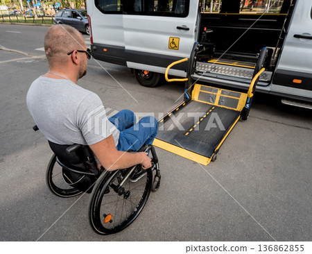 A man in a wheelchair moves to the lift of a specialized vehicle A man in a wheelchair moves to the lift of a specialized vehicle 136862855