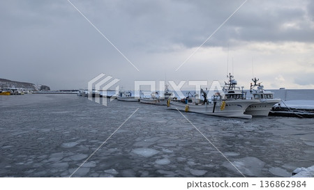 Fishing boats moored at Rausu Port in winter. Scenery of the Shiretoko mountain range and port. Fishing boats moored at Rausu Port in winter. Scenery of the Shiretoko mountain range and port. 136862984