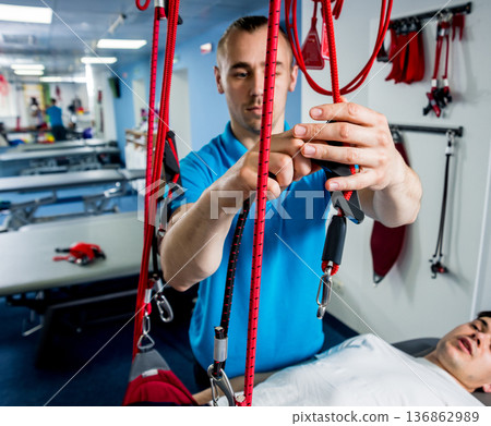 Physiotherapy. Suspension training therapy. Young man doing fitness traction 136862989
