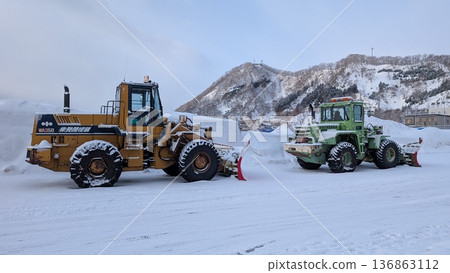 冬季港口，除雪車、輪式裝載機和重型機械都在作業，推著雪。 136863112