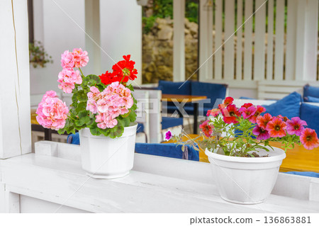 Outdoor cafe terrace with colorful decorative flowers in pots, cozy summer restaurant seating area Outdoor cafe terrace with colorful decorative flowers in pots, cozy summer restaurant seating area 136863881