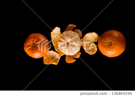 The ripe fruit of the citrus plant mandarin, peeled and also not peeled, on a black background The ripe fruit of the citrus plant mandarin, peeled and also not peeled, on a black background 136864294