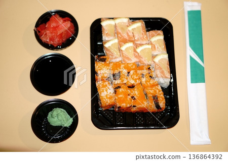 a set of sushi rolls in a plastic container and additional spices in a plastic bowl a set of sushi rolls in a plastic container and additional spices in a plastic bowl 136864392