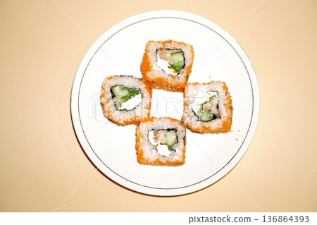 Sushi rolls lie in a white plate on an orange background Sushi rolls lie in a white plate on an orange background 136864393