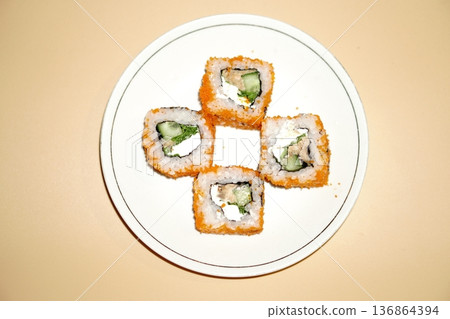Sushi rolls lie in a white plate on an orange background Sushi rolls lie in a white plate on an orange background 136864394