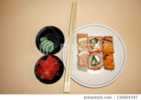 Sushi rolls lie in a white plate on an orange background Sushi rolls lie in a white plate on an orange background 136864397