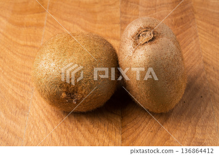 Two kiwi lie on a wooden board Two kiwi lie on a wooden board 136864412