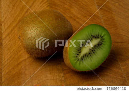 Kiwi one whole and cut off part lie on a wooden board Kiwi one whole and cut off part lie on a wooden board 136864418