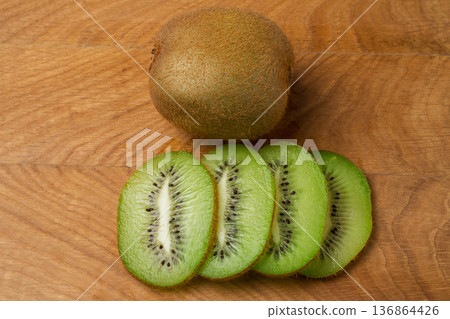 Kiwi single whole and sliced on a wooden board Kiwi single whole and sliced on a wooden board 136864426