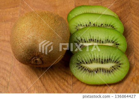 Kiwi single whole and sliced on a wooden board Kiwi single whole and sliced on a wooden board 136864427