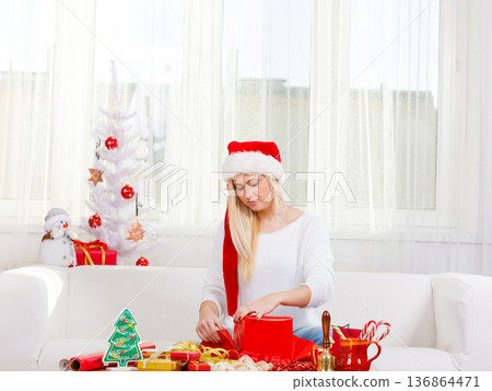Woman in Santa hat opening christmas gifts Woman in Santa hat opening christmas gifts 136864471