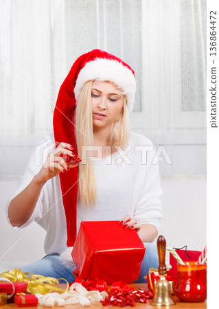 Woman in Santa hat opening christmas gifts Woman in Santa hat opening christmas gifts 136864472
