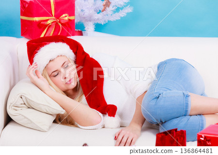 girl wearing santa hat sleeping on sofa at home 136864481