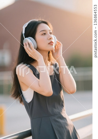 女孩戴耳机聆听音乐享受阳光 136864553