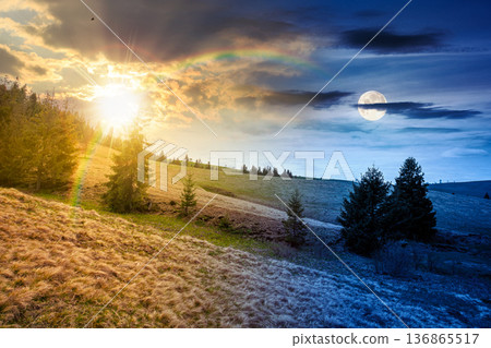 rolling hill with green field under cloudy sky in spring. day and night time change concept. scenic view countryside landscape in mountains with sun and moon at twilight. equality and shift template 136865517