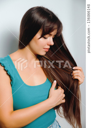 Long hair styling in a simple indoor setting with a woman enjoying her hair care routine Long hair styling in a simple indoor setting with a woman enjoying her hair care routine 136866148