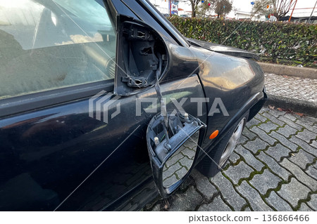 Broken car side mirror hanging from black vehicle door with exposed wires after accident damage close up outdoors. Broken car side mirror hanging from black vehicle door with exposed wires after accident damage close up outdoors. 136866466
