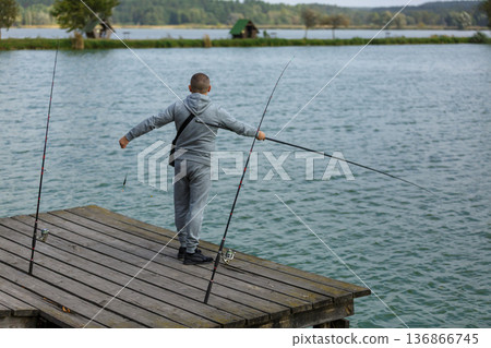 Man fishing from wooden lake pier Man fishing from wooden lake pier 136866745