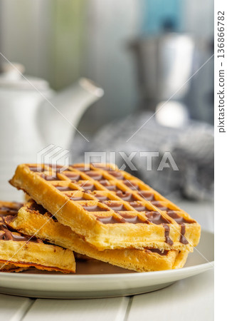 Sweet waffles with chocolate on plate on kitchen table. Sweet waffles with chocolate on plate on kitchen table. 136866782