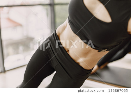 Focus on woman's torso. Three young fit women training in gym. Women wearing black sportwear. Focus on woman's torso. Three young fit women training in gym. Women wearing black sportwear. 136867065