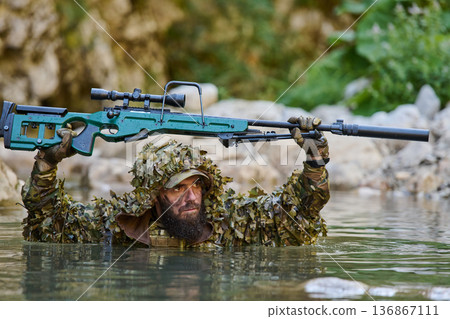 Camouflaged Sniper Soldier Wading Through Water Holding Scoped Rifle Above Head in River Camouflaged Sniper Soldier Wading Through Water Holding Scoped Rifle Above Head in River 136867111