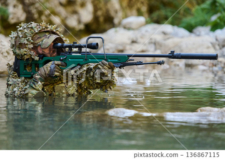 Camouflaged Sniper Soldier Aiming Rifle From Shallow Water in Tactical Ghillie Suit Camouflaged Sniper Soldier Aiming Rifle From Shallow Water in Tactical Ghillie Suit 136867115